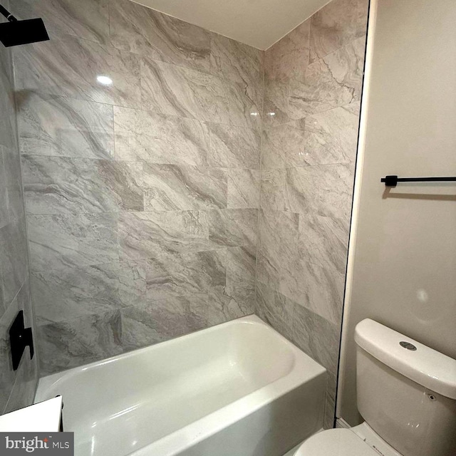 bathroom featuring tiled shower / bath combo and toilet