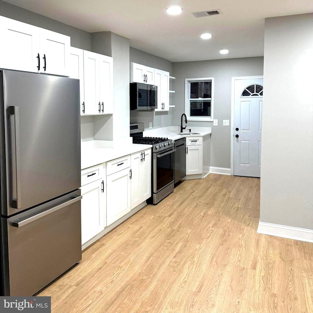 kitchen with light hardwood / wood-style floors, stainless steel appliances, white cabinetry, and sink