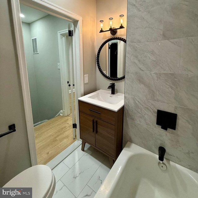 bathroom featuring a bathtub, vanity, and toilet