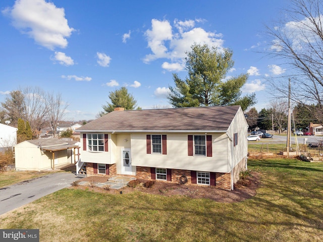 split foyer home featuring a front yard and a storage unit