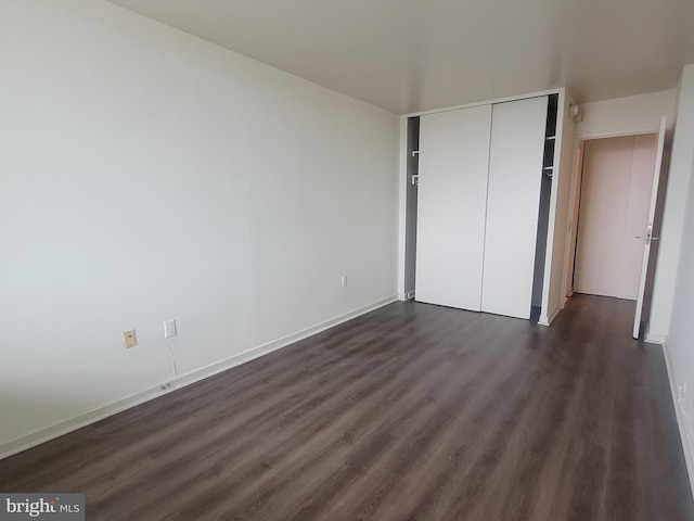 unfurnished bedroom featuring a closet and dark wood-type flooring