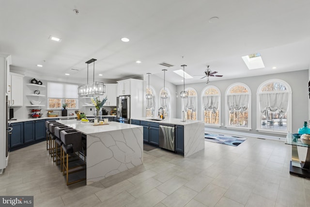 kitchen featuring blue cabinetry, a center island, white cabinetry, and decorative light fixtures