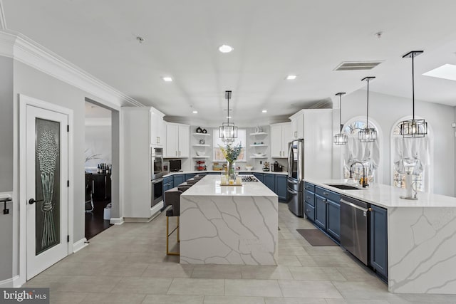 kitchen featuring decorative light fixtures, stainless steel appliances, white cabinetry, blue cabinets, and sink