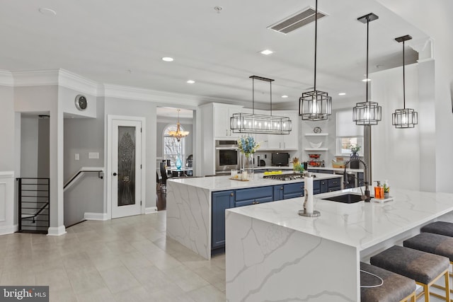 kitchen with blue cabinetry, a large island with sink, a breakfast bar, white cabinets, and sink