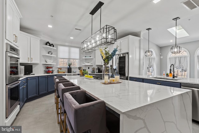 kitchen featuring stainless steel appliances, blue cabinetry, white cabinetry, and a center island