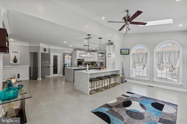 kitchen with a large island, a skylight, ceiling fan, pendant lighting, and a kitchen bar