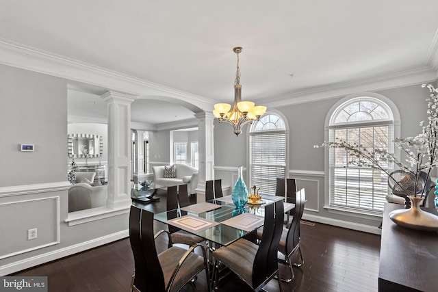 dining area featuring ornamental molding, dark hardwood / wood-style floors, a chandelier, and ornate columns