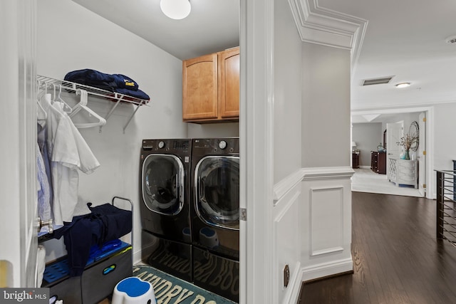 washroom with washing machine and dryer, dark hardwood / wood-style flooring, crown molding, and cabinets