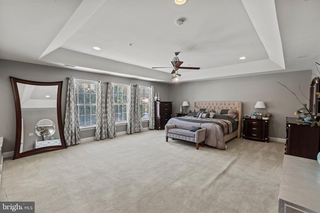 carpeted bedroom with ceiling fan and a raised ceiling