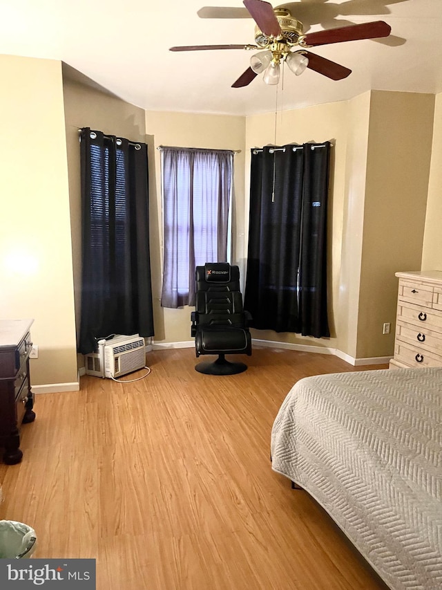 bedroom with light hardwood / wood-style floors, an AC wall unit, and ceiling fan