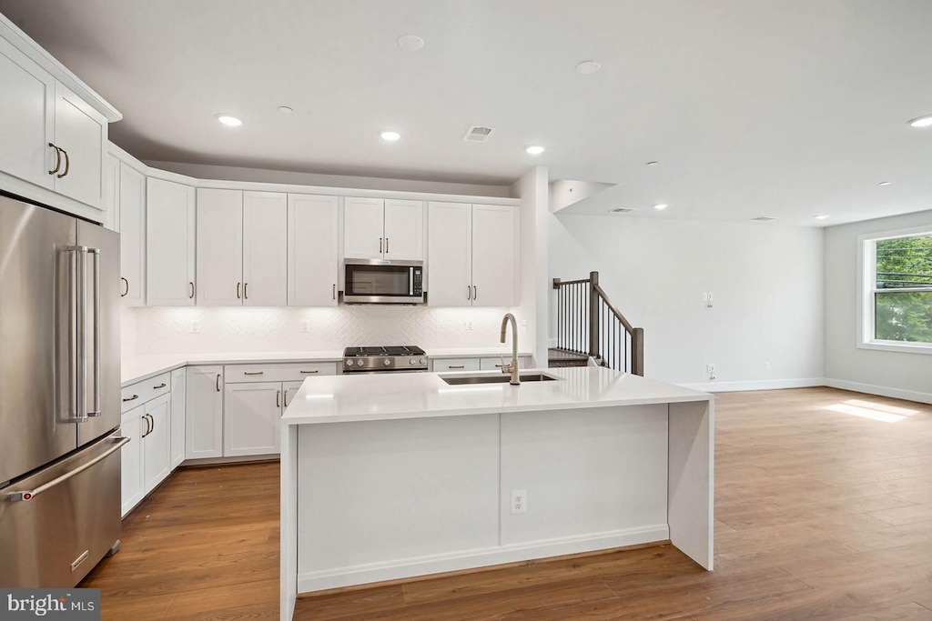 kitchen with white cabinets, sink, an island with sink, and stainless steel appliances