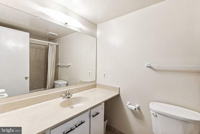 bathroom with walk in shower, vanity, and toilet