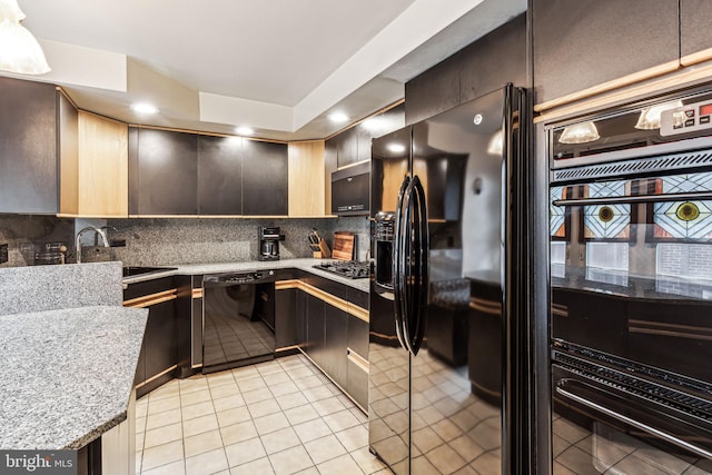 kitchen with sink, tasteful backsplash, light stone counters, light tile patterned flooring, and black appliances