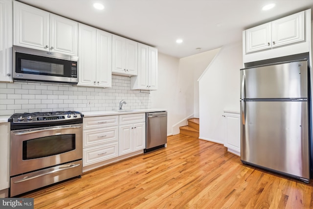 kitchen featuring appliances with stainless steel finishes, light countertops, light wood-style flooring, and white cabinetry