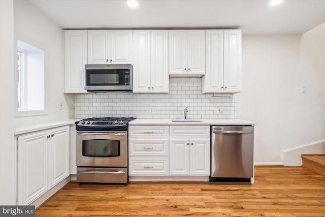 kitchen featuring stainless steel appliances, light wood-type flooring, white cabinets, and light countertops