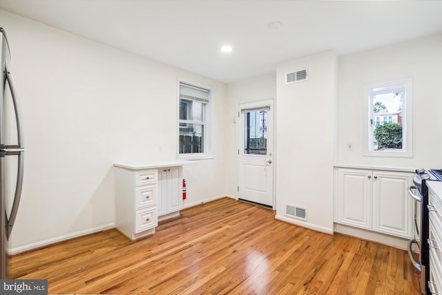 kitchen featuring stainless steel appliances, white cabinets, visible vents, and light wood-style floors