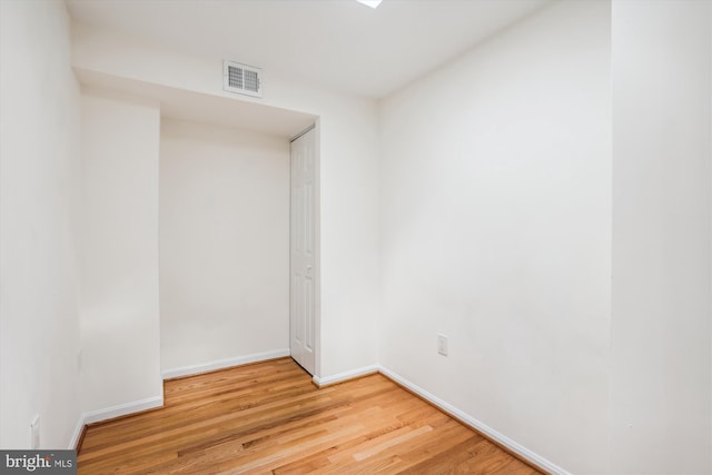 unfurnished room featuring baseboards, visible vents, and wood finished floors