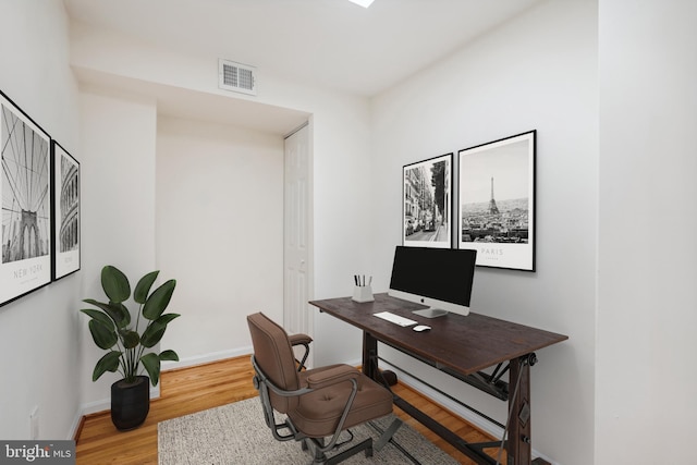 office space with wood finished floors, visible vents, and baseboards