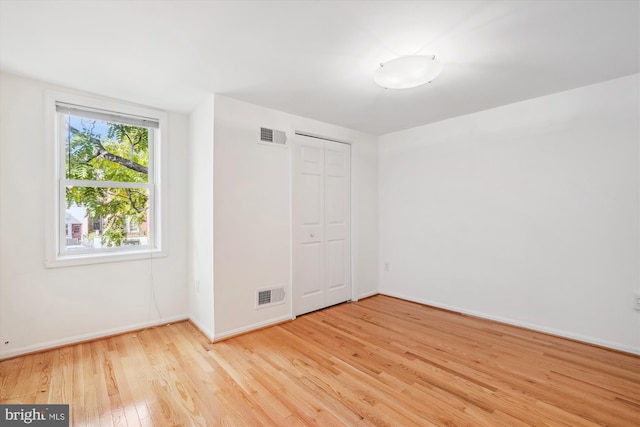 unfurnished bedroom with light wood-style floors, baseboards, visible vents, and a closet