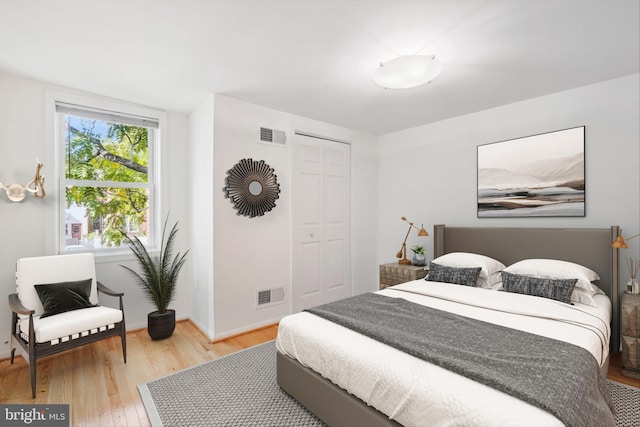 bedroom with light wood-type flooring, a closet, visible vents, and baseboards