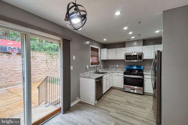 kitchen featuring pendant lighting, white cabinets, sink, appliances with stainless steel finishes, and light stone counters