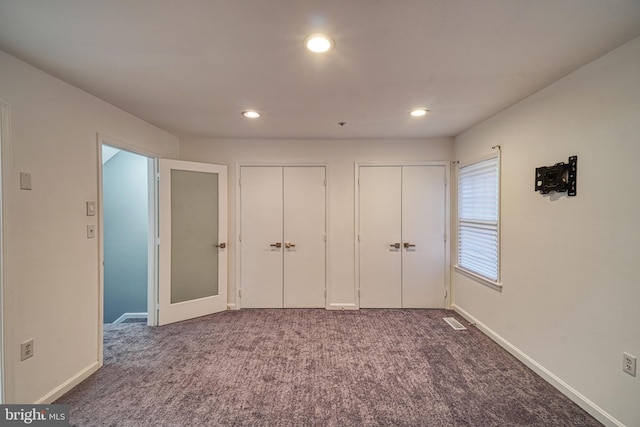 unfurnished bedroom featuring carpet floors and multiple closets