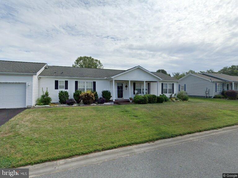 ranch-style home with covered porch, a garage, and a front lawn