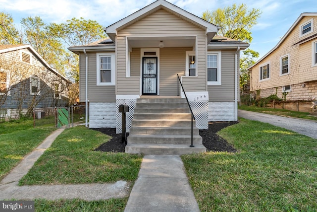 bungalow with covered porch and a front lawn