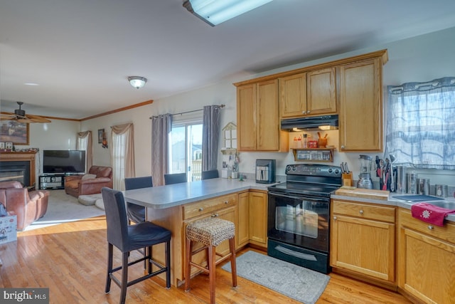 kitchen featuring kitchen peninsula, a kitchen breakfast bar, ceiling fan, light hardwood / wood-style flooring, and black electric range oven