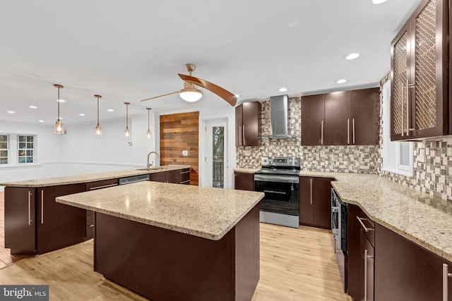 kitchen with pendant lighting, wall chimney exhaust hood, light stone countertops, appliances with stainless steel finishes, and a kitchen island