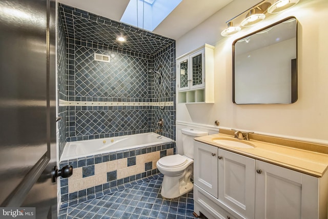 full bathroom featuring a skylight, tile patterned floors, vanity, tiled shower / bath combo, and toilet