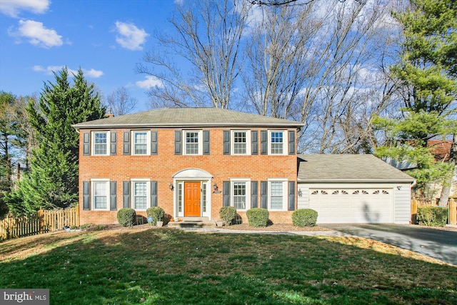 colonial inspired home featuring a garage and a front lawn