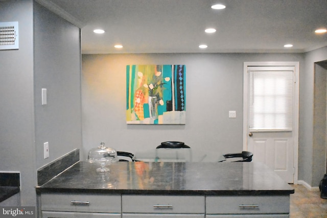 kitchen with crown molding, gray cabinets, and kitchen peninsula