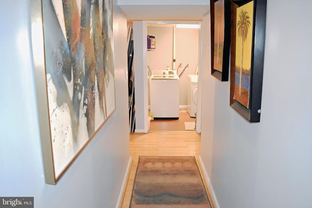 corridor featuring wood-type flooring and independent washer and dryer