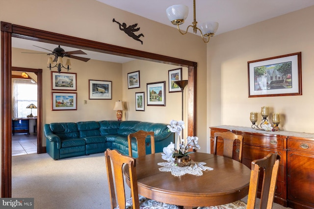 carpeted dining space featuring ceiling fan with notable chandelier