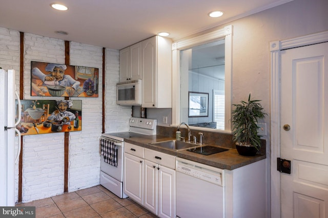 kitchen featuring brick wall, white appliances, sink, white cabinets, and light tile patterned flooring