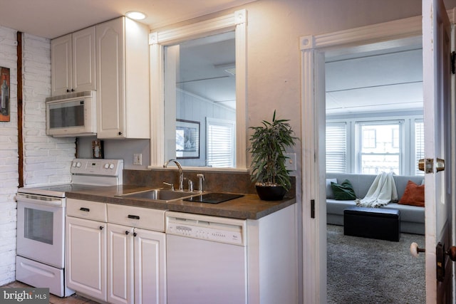 kitchen with white cabinets, white appliances, sink, and brick wall