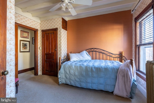 carpeted bedroom with ceiling fan and beamed ceiling