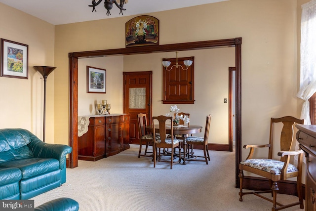 carpeted dining room featuring an inviting chandelier