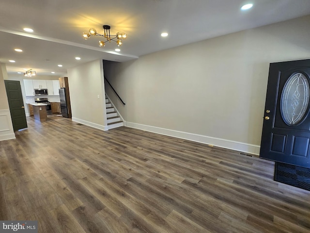 entrance foyer with a notable chandelier, dark wood finished floors, recessed lighting, baseboards, and stairs