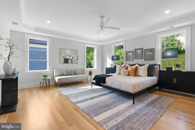 bedroom featuring ceiling fan, light hardwood / wood-style floors, ornamental molding, and a tray ceiling