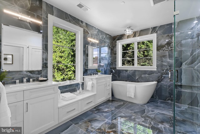 bathroom with vanity, tasteful backsplash, tile walls, and independent shower and bath