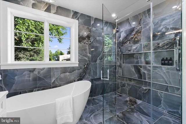 bathroom featuring shower with separate bathtub and tile walls