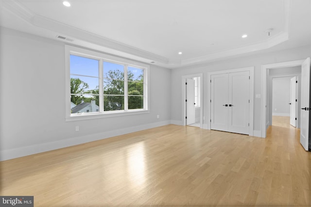 unfurnished bedroom featuring light wood-type flooring, ornamental molding, and a tray ceiling