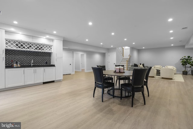 dining space featuring wet bar and light hardwood / wood-style flooring