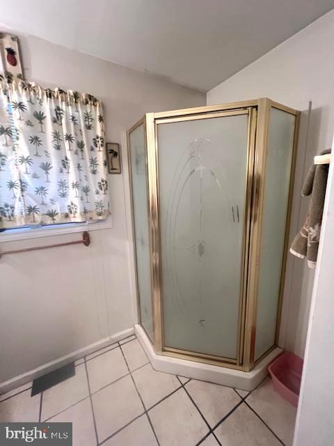 bathroom with tile patterned flooring, a shower with shower door, and lofted ceiling