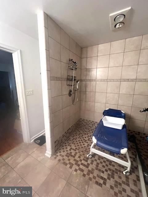 bathroom with tile patterned flooring and a tile shower