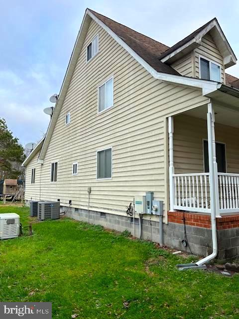 view of property exterior featuring a lawn, central AC, and covered porch