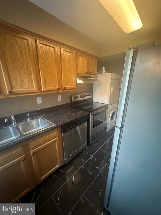 kitchen with sink, stainless steel appliances, and stacked washer / drying machine