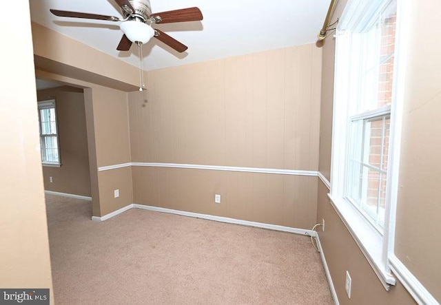 spare room with ceiling fan, light carpet, and plenty of natural light